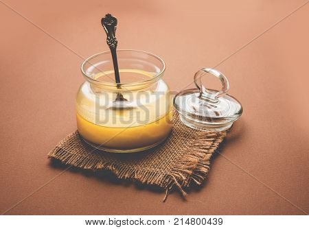 Desi Ghee or clarified butter in glass or Copper container or ceramic jar with spoon, selective focus