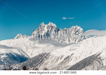 Beautiful winter landscape of high mountain slopes with bright white snow under the clear blue sky