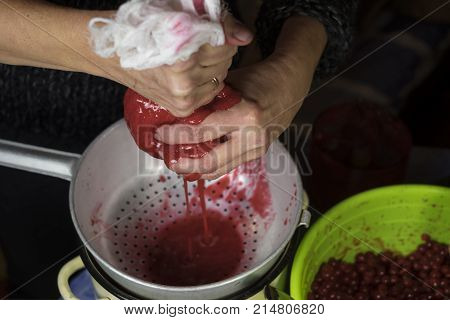 Female hands squeezing red berries using strainer and cloth closeup indoor shot
