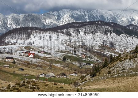 Winter rural landscape with traditional farm houses near Piatra Craiului massif in Sirnea village, Brasov county, Romania.