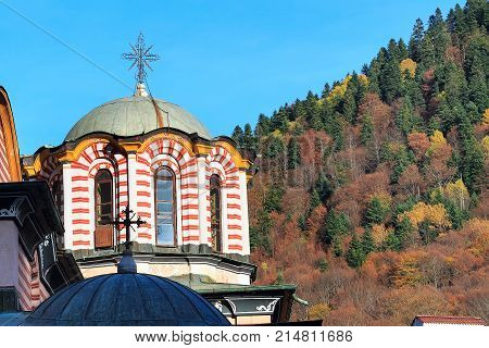 Rila monastery, Bulgaria church dome and cross close-up and autumn mountain trees at background