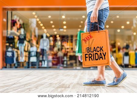 Closeup woman holding shopping bags in the shopping mall with Black Friday words concpt.