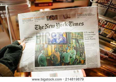 STRASBOURG FRANCE - NOV 21 2017: POV of male hand wearing gloves holding the New York Times newspaper featuring news about Mugabe's fall