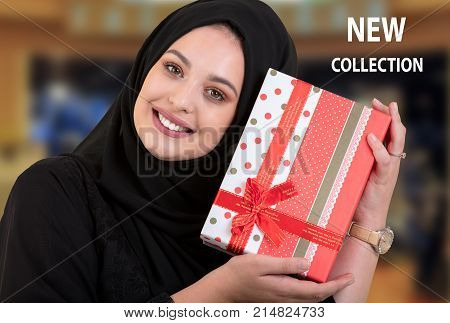 Happy young muslim woman with shopping bag and gift boxes at shopping mall