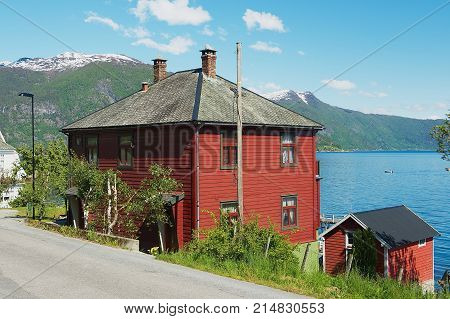 BALESTRAND, NORWAY - JUNE 06, 2012: Exterior of a traditional red painted Norwegian house with Sognefjord at the background in Balestrand, Norway.
