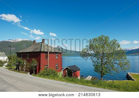 BALESTRAND, NORWAY - JUNE 06, 2012: View to the traditional red painted Norwegian house with Sognefjord at the background in Balestrand, Norway.