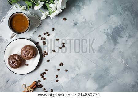 Chocolate cupcakes with a cup of hot black coffee on cocrete background. Top view and copy space