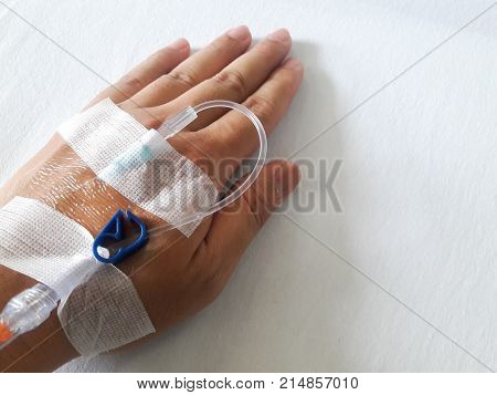 Patient Hand With The Tube Of Normal Saline Infusion On White Cloth Background