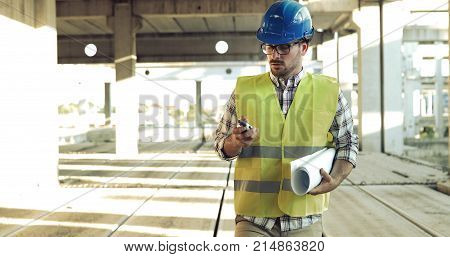 Male architect communicating on walkie-talkie at building site