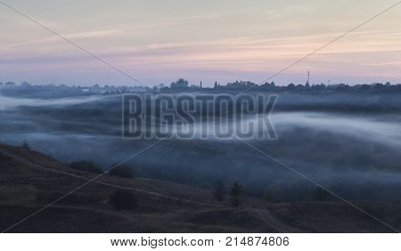 Morning autumn landscape: fog over hills and forest. View from above. Village Opishnya Poltava region Ukraine