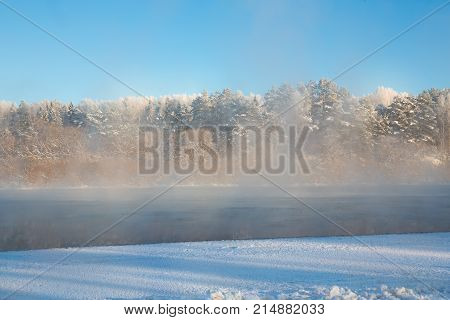 Morning steam fog above river. Winter landscape. Frosty day on the river. Part of the river is covered with ice. Swirl the water vapor. Harmonious colours. The texture is horizontal. Place for text.