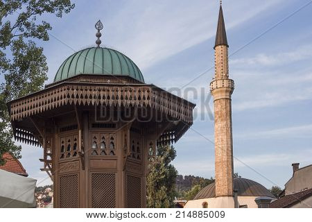 SARAJEVO, BOSNIA AND HERZEGOVINA - AUGUST 18 2017: Architectural close up of the top of Sebilj fountain and mosque minaret in Sarajevo city centre