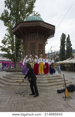 SARAJEVO, BOSNIA AND HERZEGOVINA - AUGUST 20 2017: Women wearing traditional Bosnian ethnic clothing in front of the Sebilj fountain on Bascarsija city centre