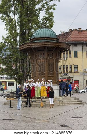 SARAJEVO, BOSNIA AND HERZEGOVINA - AUGUST 20 2017: Women wearing traditional Bosnian ethnic clothing in front of the Sebilj fountain on Bascarsija city centre