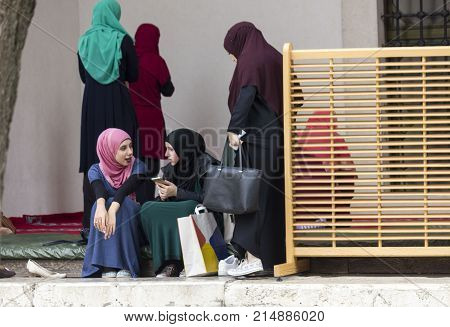 SARAJEVO, BOSNIA AND HERZEGOVINA - AUGUST 20 2017: three islamic girls sit in the courtyard of Gazi husrev beg Mosque in Sarajevo
