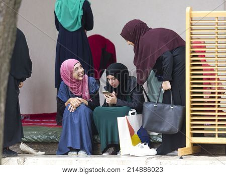 SARAJEVO, BOSNIA AND HERZEGOVINA - AUGUST 20 2017: three islamic girls sit in the courtyard of Gazi husrev beg Mosque in Sarajevo