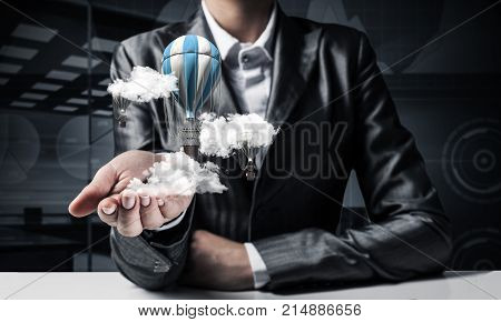 Closeup of business woman in suit presenting flying aerostate among clouds in her palm with dark office view on background. 3D rendering.