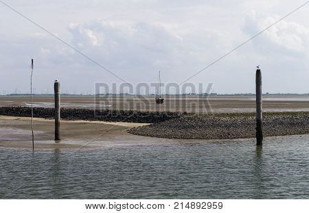Image shows a stranded sailboat at low tide in the sand