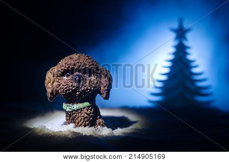 Toy Dog - A Symbol Of The New Year Under The Snow Against The Background Of Fir Branches. Toy's Dog 