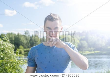 The young man in the background of the pond. Summer. Portrait.