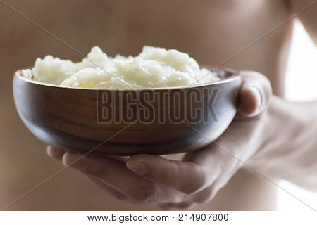 A young man holding a wooden bowl of rice porridge. The concept of a healthy Breakfast.