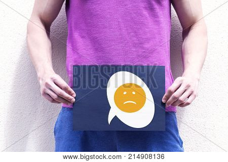 A young man holds a placard at the level of the genitals