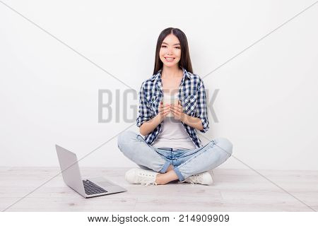 Attractive, Cute, Charming Girl Sitting On The Floor With Crosssed-legs Near Wall, Holding Mug Of Te