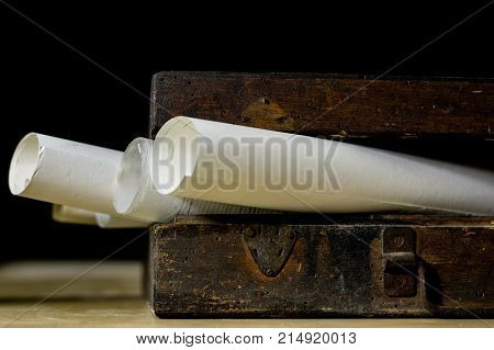 Old Rolls And Plans In Folded Paper Rolls. Old Book And Case. Documents On An Old Wooden Table.