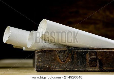 Old Rolls And Plans In Folded Paper Rolls. Old Book And Case. Documents On An Old Wooden Table.