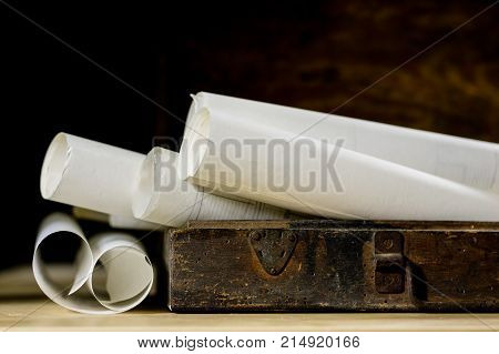 Old Rolls And Plans In Folded Paper Rolls. Old Book And Case. Documents On An Old Wooden Table.
