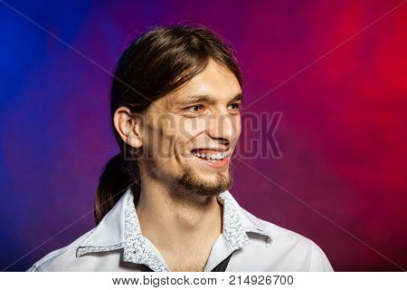 Fashion masculinity concept. Smiling man with long hairs. Young male cheering on colorful red blue background.