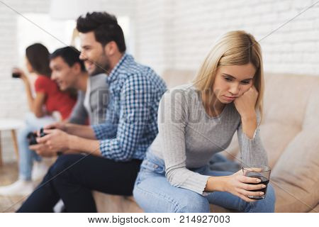 Two guys and two girls play on the game console. They are sitting on the couch and holding the joysticks. Girls are offended by the guys.