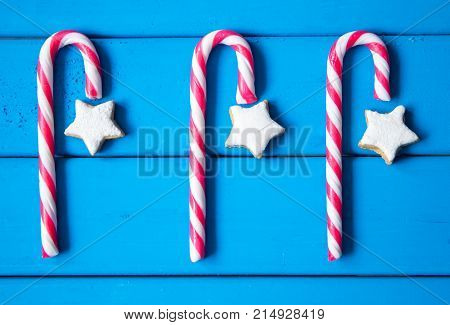 Christmas composition with star-shaped gingerbread cookies and candies on blue background. top view