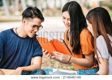 A group of young or teen asian student in university smiling and reading the book and look at the tablet or labtop computer in summer holiday.