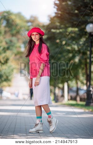 Asian woman fashion photo. Beautiful mixed race asian caucasian young girl in pink hat jaket boots and red sunglasses looking at camera outdoor against green blurred bokeh nature background. Gorgeous slim model posingi n trendy casual colourful in full-le