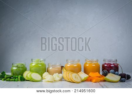 Colorful baby food purees in glass jars with ingredients. Healthy organic baby food concept. Starting solid food, delivery
