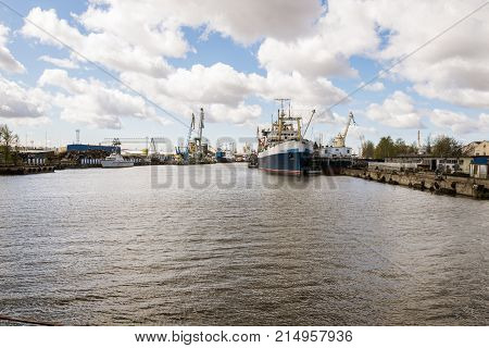 Port barge and embankment of Kaliningrad with ships. A bright day with clouds. Pregolya river.