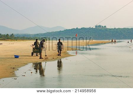 Goa, India - November 23, 2012: A team of workers begin clearing the Cavelossim Beach from plastic bottles and other trash, South Goa, India.