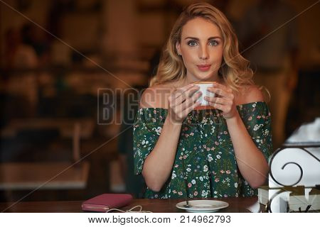 Attractive young woman drinking coffee in coffeshop