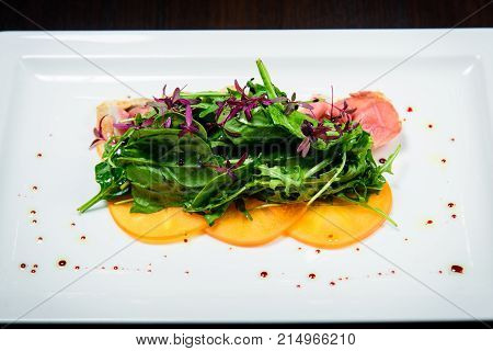 Salad With Fried Bacon Herbs And Orange Fruit In White Plate With Black Background