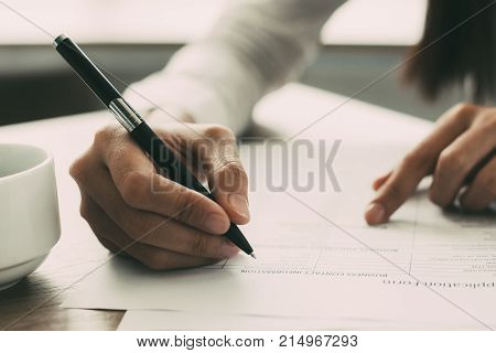 Cropped view of woman holding pen and filling out application form at table