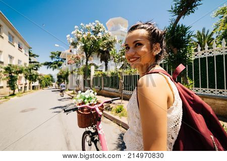 Smiling eastern girl on vintage bicycle with backet of flowers
