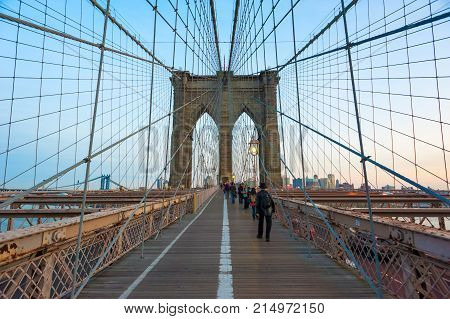 New york City, USA - Nov 14, 2011: People walking on the Brooklyn bridge at dusk.