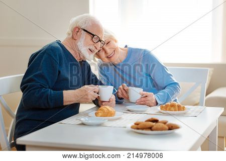 Love you. Cheerful pensioner couple expressing positivity while having breakfast and looking forward