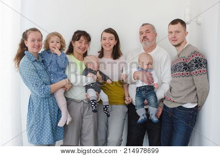 People of different ages with kids posing all together looking happily at camera.