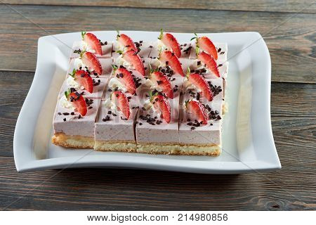 Plate with sliced cheesecake decorated with chocolate crust and strawberries placed on wooden table restaurant cafe coffee shop bakery baking cooking pastry sweer dessert concept.