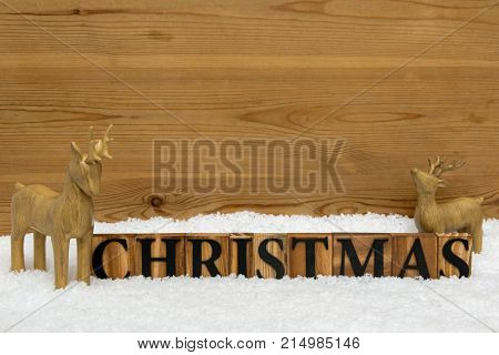 The word Christmas with two wooden reindeer in snow, copy space for you own message.