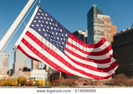 US flag floating with New-York city buildings in the background, USA