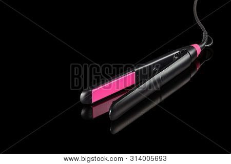 Electrical Hair Iron For Household On The Black Mirror Background With Copy Space
