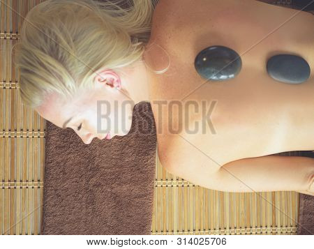 Young woman in spa salon, getting stones massage